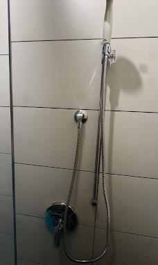 New chrome shower valve with hand shower on a tiled wall