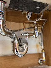 Rebuilt chrome P-trap and supply valves under a kitchen sink