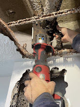 Plumber cutting through an old cast iron drain pipe with a power cutter